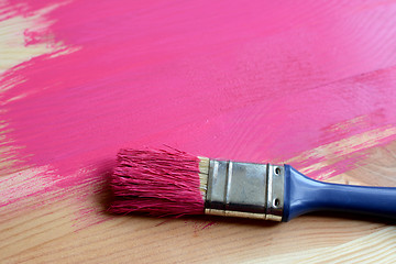 Image showing Paint-covered paintbrush on painted wood