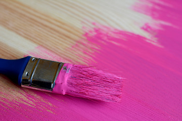 Image showing Used paintbrush on half-painted pine board