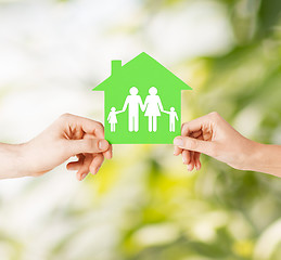 Image showing hands holding green house with family