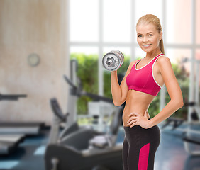 Image showing smiling woman with heavy steel dumbbell