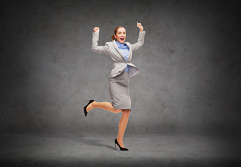 Image showing happy woman jumping with hands up