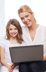 Image showing smiling mother and little girl with laptop at home