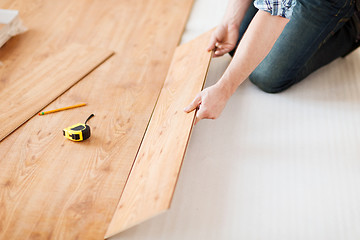 Image showing close up of male hands intalling wood flooring