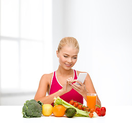 Image showing woman with vegetables pointing at smartphone