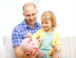 Image showing happy father and daughter with big piggy bank