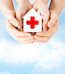 Image showing hands holding paper house with red cross