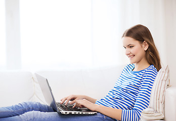 Image showing smiling teenage girl with laptop computer at home
