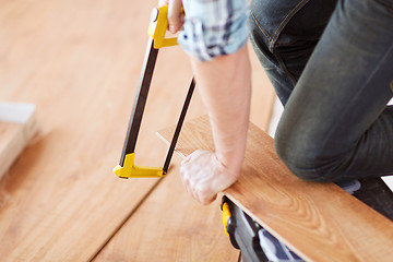 Image showing close up of male hands cutting parquet floor board