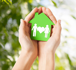 Image showing hands holding green house with family