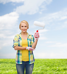 Image showing smiling woman in gloves with paint roller