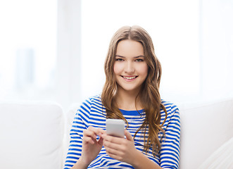 Image showing smiling teenage girl with smartphone at home