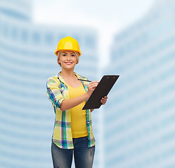 Image showing smiling woman in helmet with clipboard