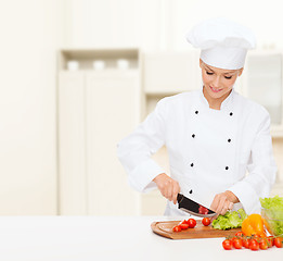 Image showing smiling female chef chopping vagetables
