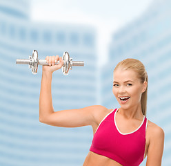 Image showing smiling woman with heavy steel dumbbell