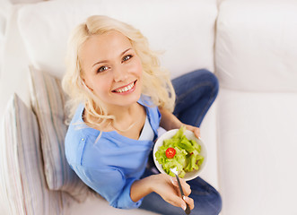 Image showing smiling young woman with green salad at home