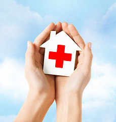 Image showing hands holding paper house with red cross