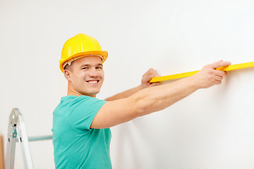 Image showing smiling man building using spirit level to measure