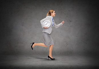 Image showing smiling young businesswoman with clock running