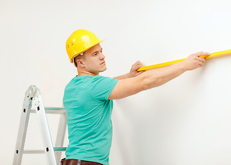 Image showing smiling man building using spirit level to measure