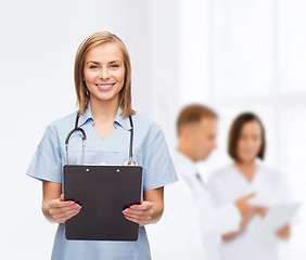 Image showing smiling female doctor or nurse with clipboard