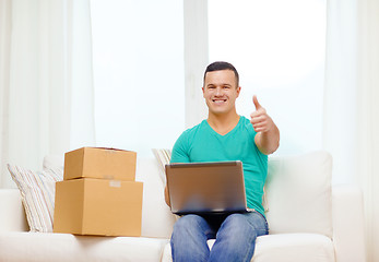 Image showing man with laptop and cardboard boxes at home