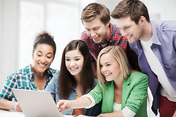 Image showing smiling students looking at laptop at school