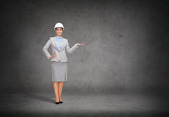 Image showing businesswoman in helmet holding something on palm