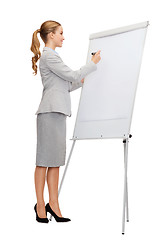 Image showing smiling businesswoman writing on flip board