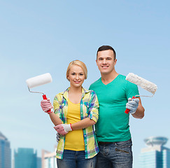 Image showing smiling couple in gloves with paint rollers