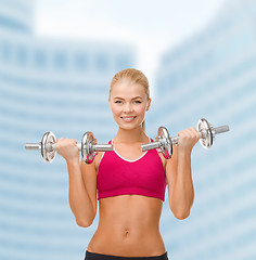 Image showing smiling woman lifting steel dumbbells