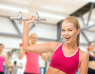 Image showing smiling woman with heavy steel dumbbell