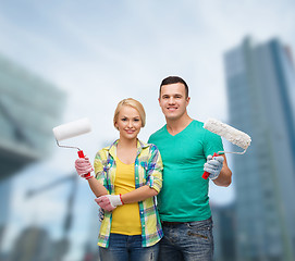 Image showing smiling couple in gloves with paint rollers