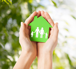 Image showing hands holding green house with family