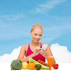 Image showing woman with vegetables pointing at smartphone