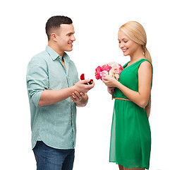 Image showing smiling couple with flower bouquet and ring