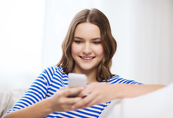 Image showing smiling teenage girl with smartphone at home