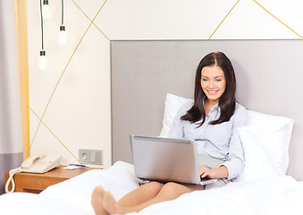 Image showing happy businesswoman with laptop in hotel room