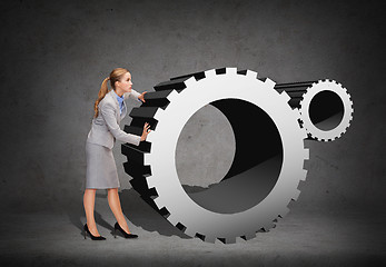 Image showing busy businesswoman pushing cogwheel