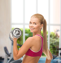 Image showing smiling woman with heavy steel dumbbell