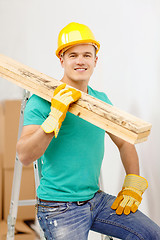 Image showing smiling manual worker in helmet with wooden boards