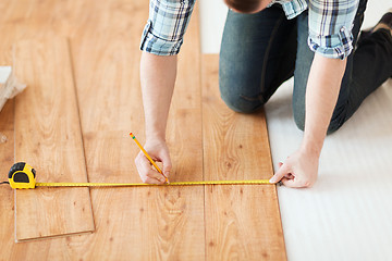 Image showing close up of male hands measuring wood flooring