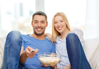 Image showing smiling couple with popcorn watching movie at home