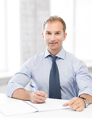 Image showing handsome businessman writing in notebook