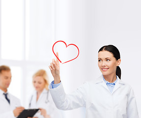 Image showing smiling female doctor pointing to heart