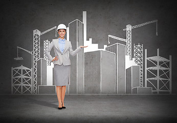 Image showing businesswoman in helmet showing construction site