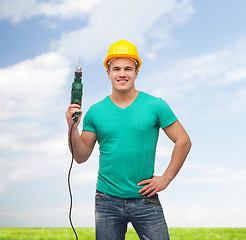 Image showing smiling manual worker in helmet with drill machine