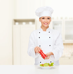 Image showing smiling female chef with preparing salad