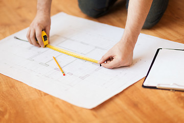 Image showing close up of male hands measuring blueprint