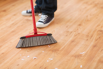 Image showing close up of male brooming wooden floor