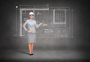 Image showing businesswoman in helmet showing blueprint